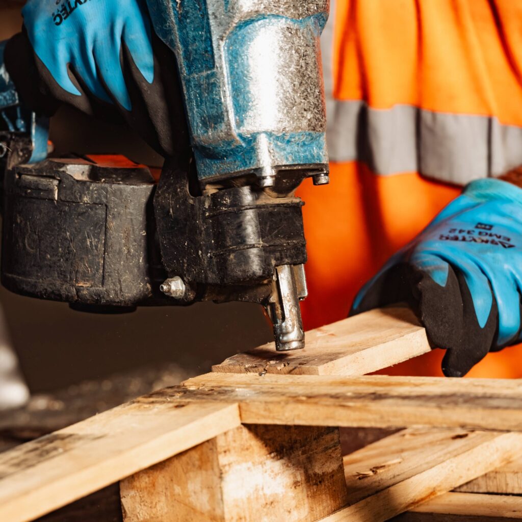 Worker repairing pallet with tool